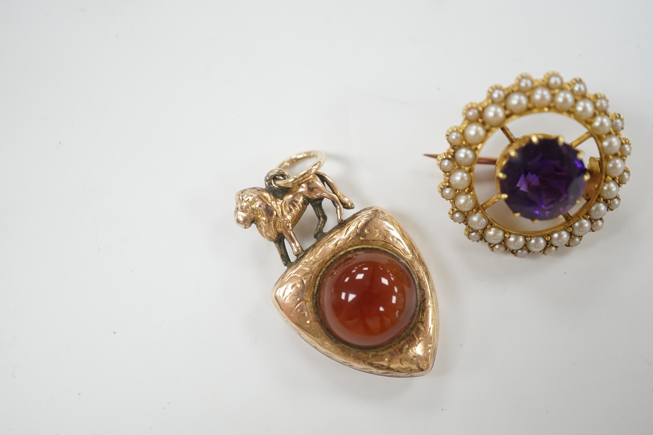 A Victorian yellow metal and two sided chalcedony set shield shaped pendant, with lion surmount, 31mm, together with an early 20th century yellow metal, amethyst and split pearl set circular brooch.